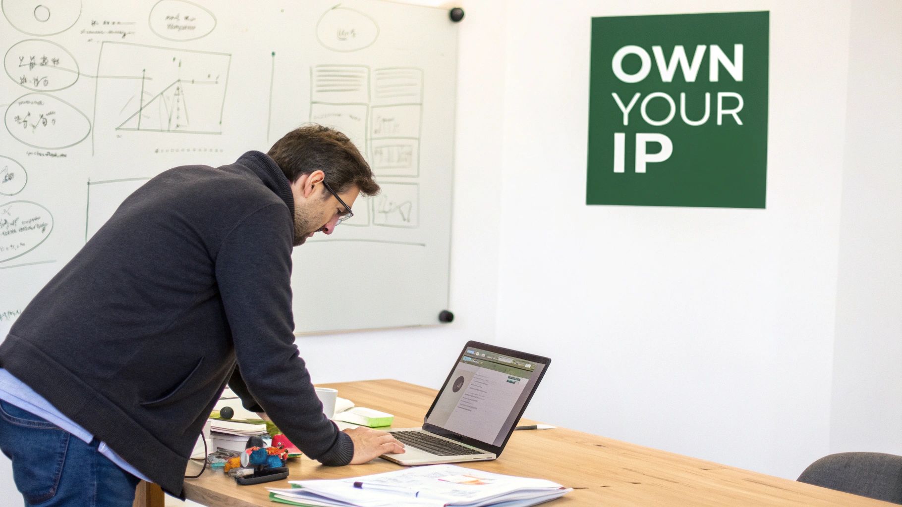 A man intently works on a laptop at a wooden desk in a modern office.