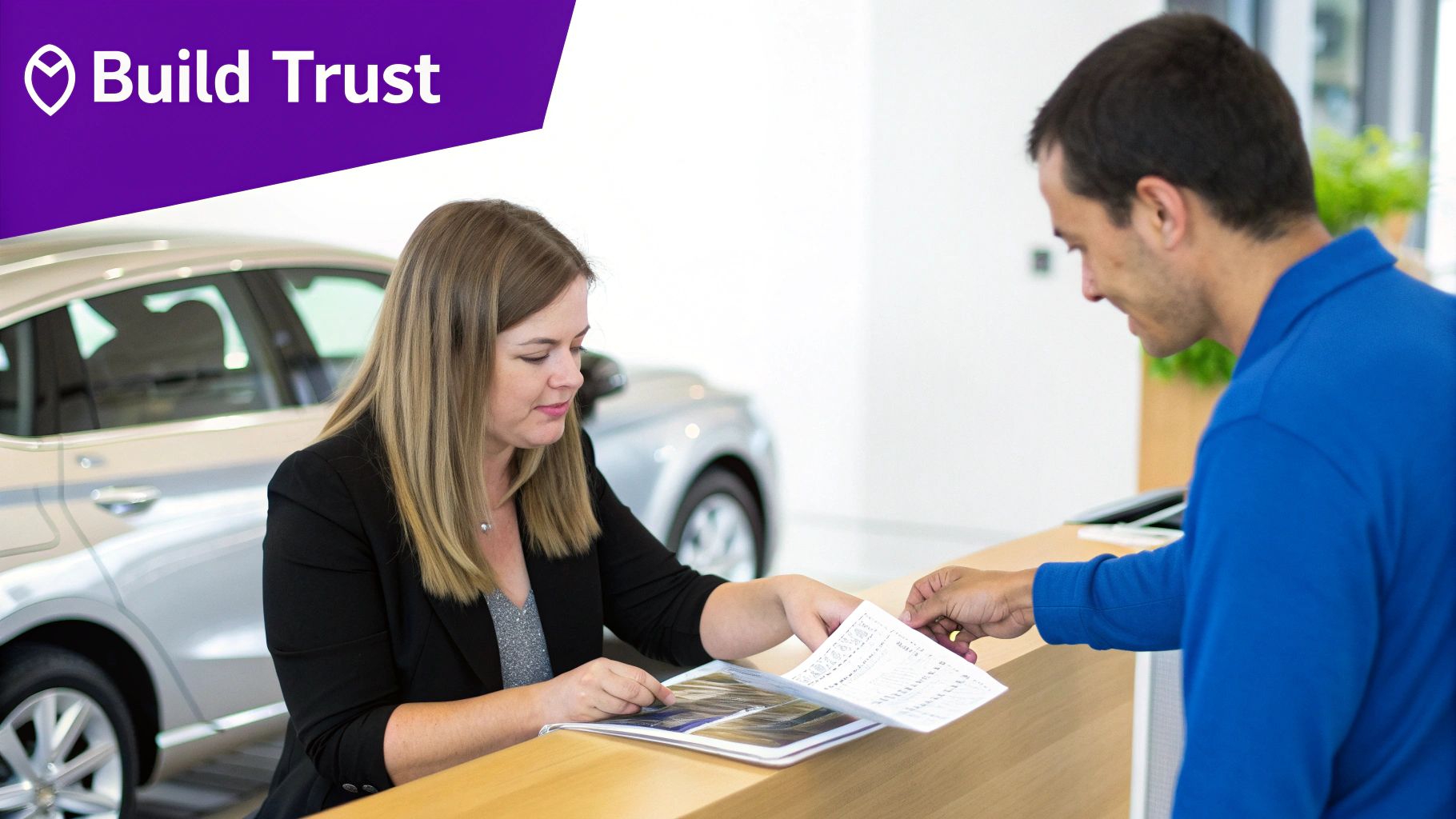 Female salesperson helping a customer with paperwork at a car showroom, with a car in the background.