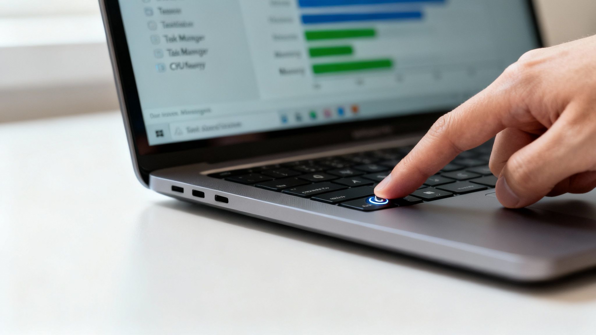 Person pressing illuminated power button on laptop keyboard to restart slow computer