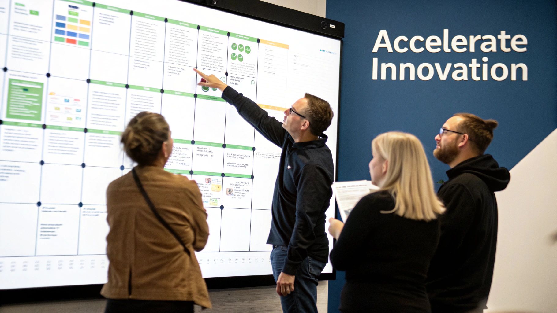 Team collaborates on a large interactive screen, pointing at project plans during an innovation workshop.