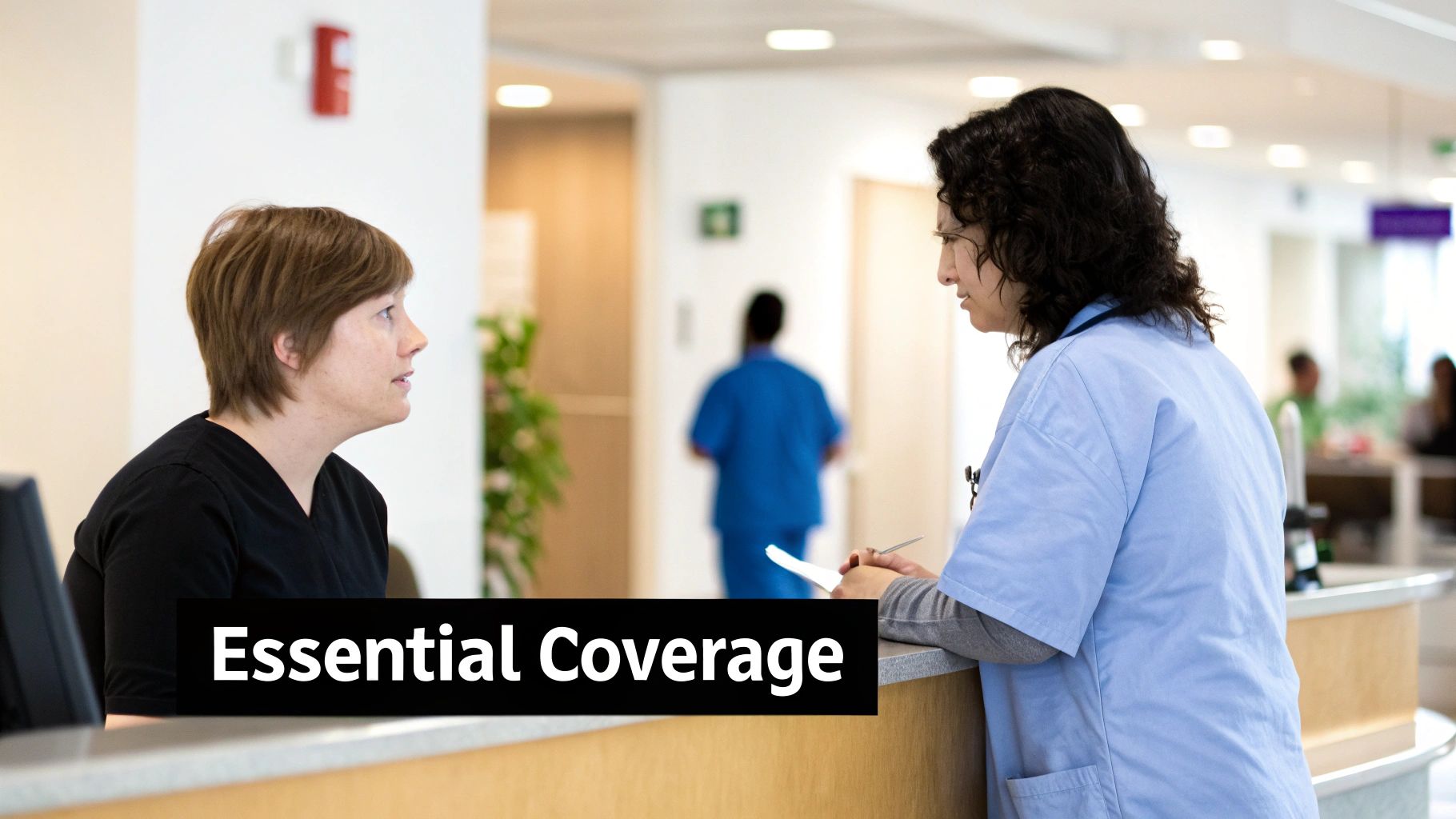 Two women discussing essential medical coverage at a hospital reception desk.