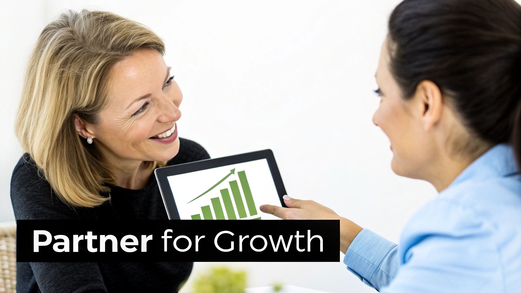 Two businesswomen discussing growth, one holding a tablet showing a green bar chart with an upward trend.