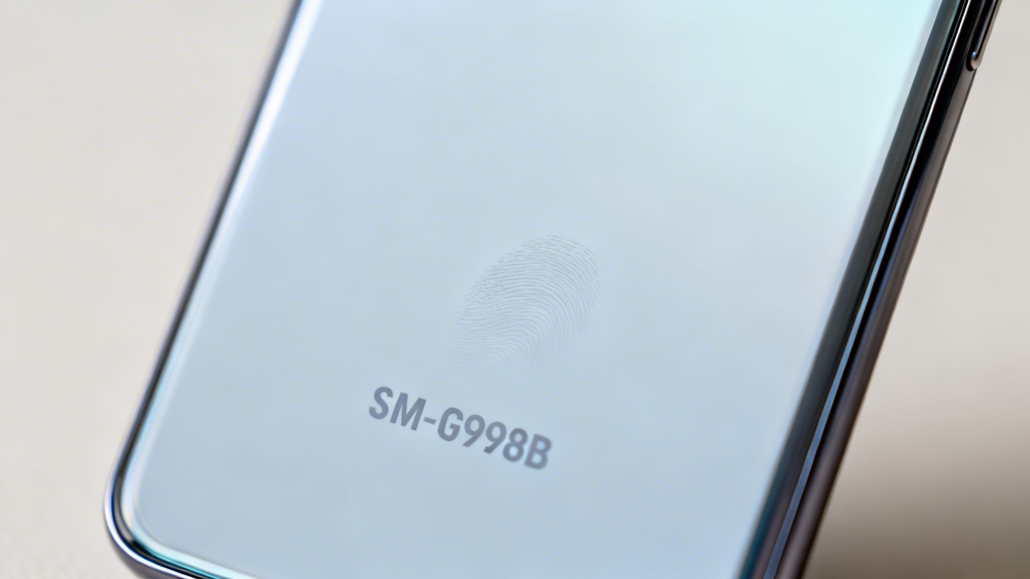 Close-up of a light blue Samsung phone back displaying a faint fingerprint and model number SM-G998B.