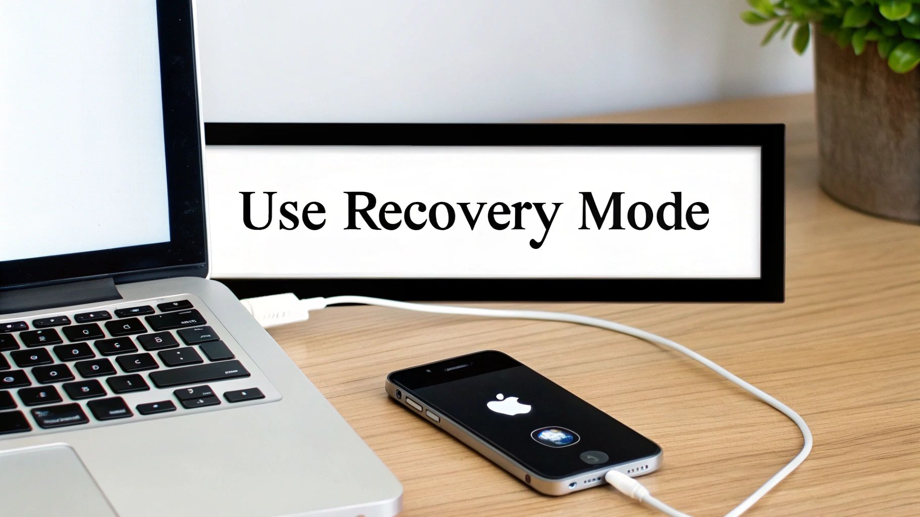 An iPhone connected to a laptop with a cable, showing the restore process on the computer screen.