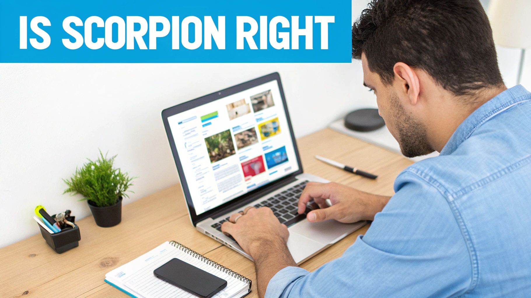 Man in a denim shirt intently working on a laptop at a clean wooden desk.