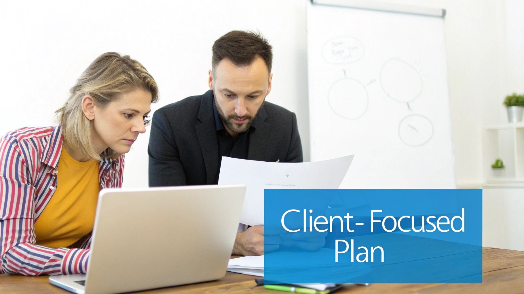 Two colleagues, a man and a woman, working together on a client-focused plan in an office.