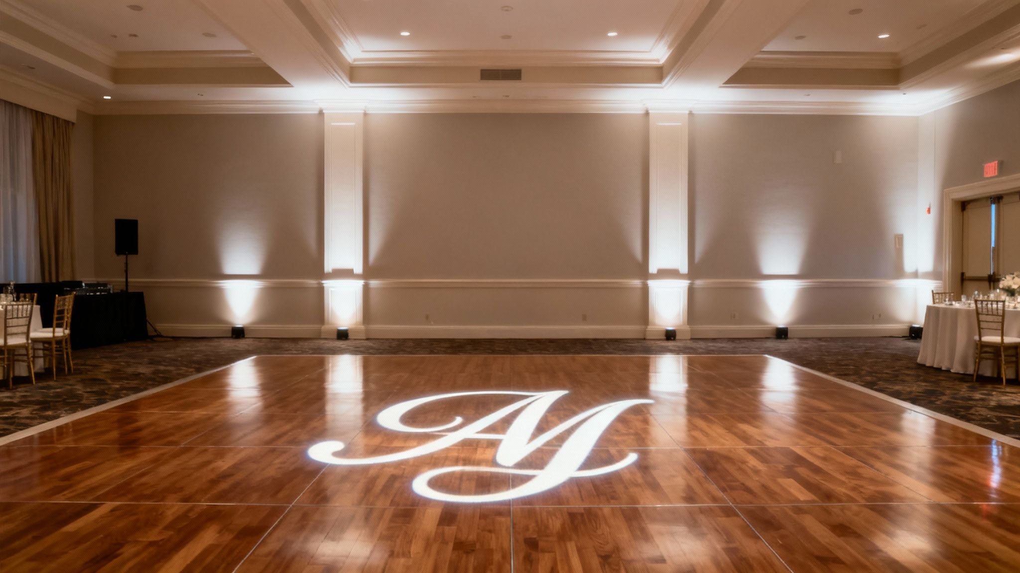 A wedding monogram projection illuminates the dance floor in a beautifully decorated venue.