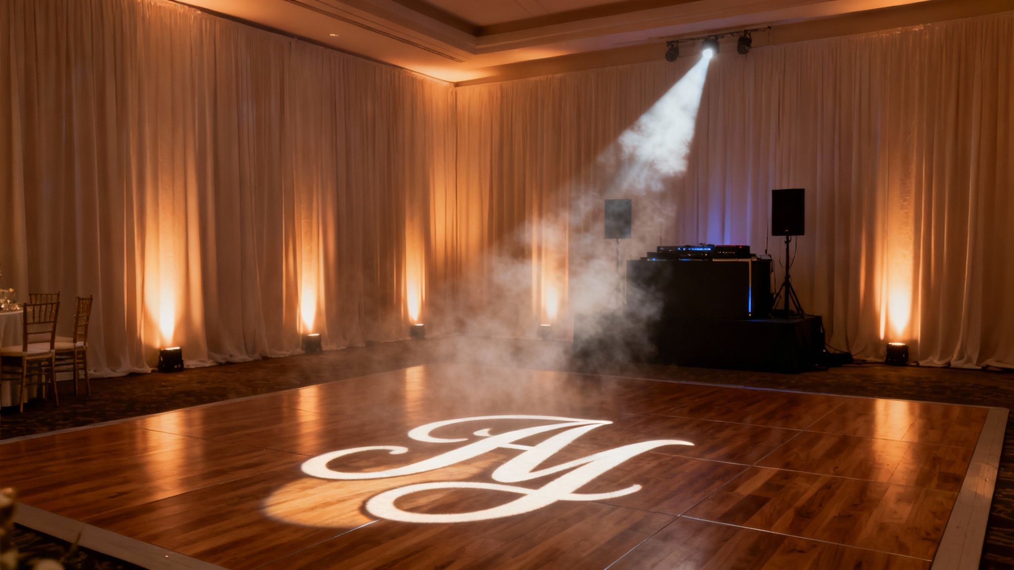 Elegant wedding reception setup with a lighted dance floor, custom monogram, DJ booth, and atmospheric effects.