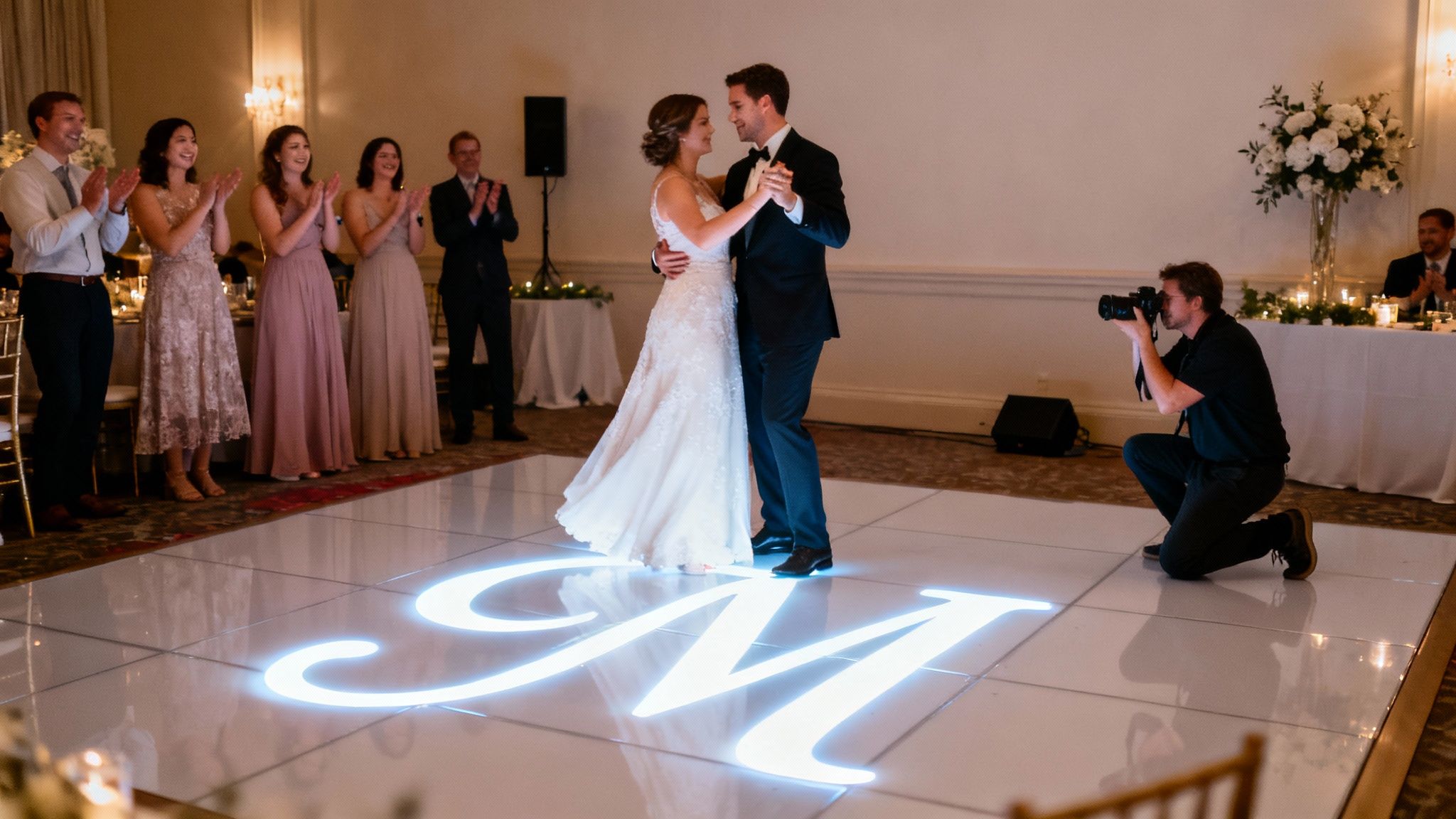 Newlyweds sharing their first dance on a lighted monogram dance floor