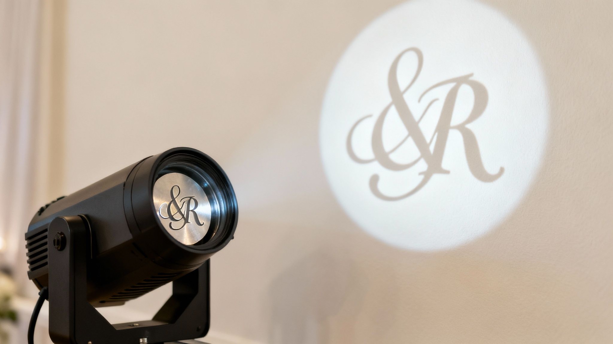 A white floral pattern gobo projected onto a brick wall, creating an elegant ambiance.