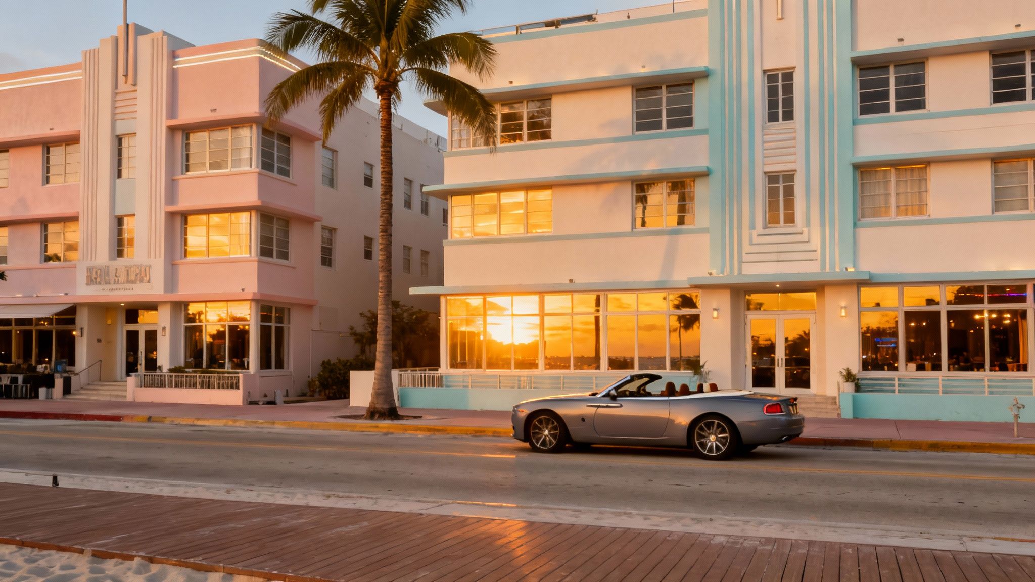 Pink and blue Art Deco hotels in Miami Beach at sunset, with a convertible car on the street.