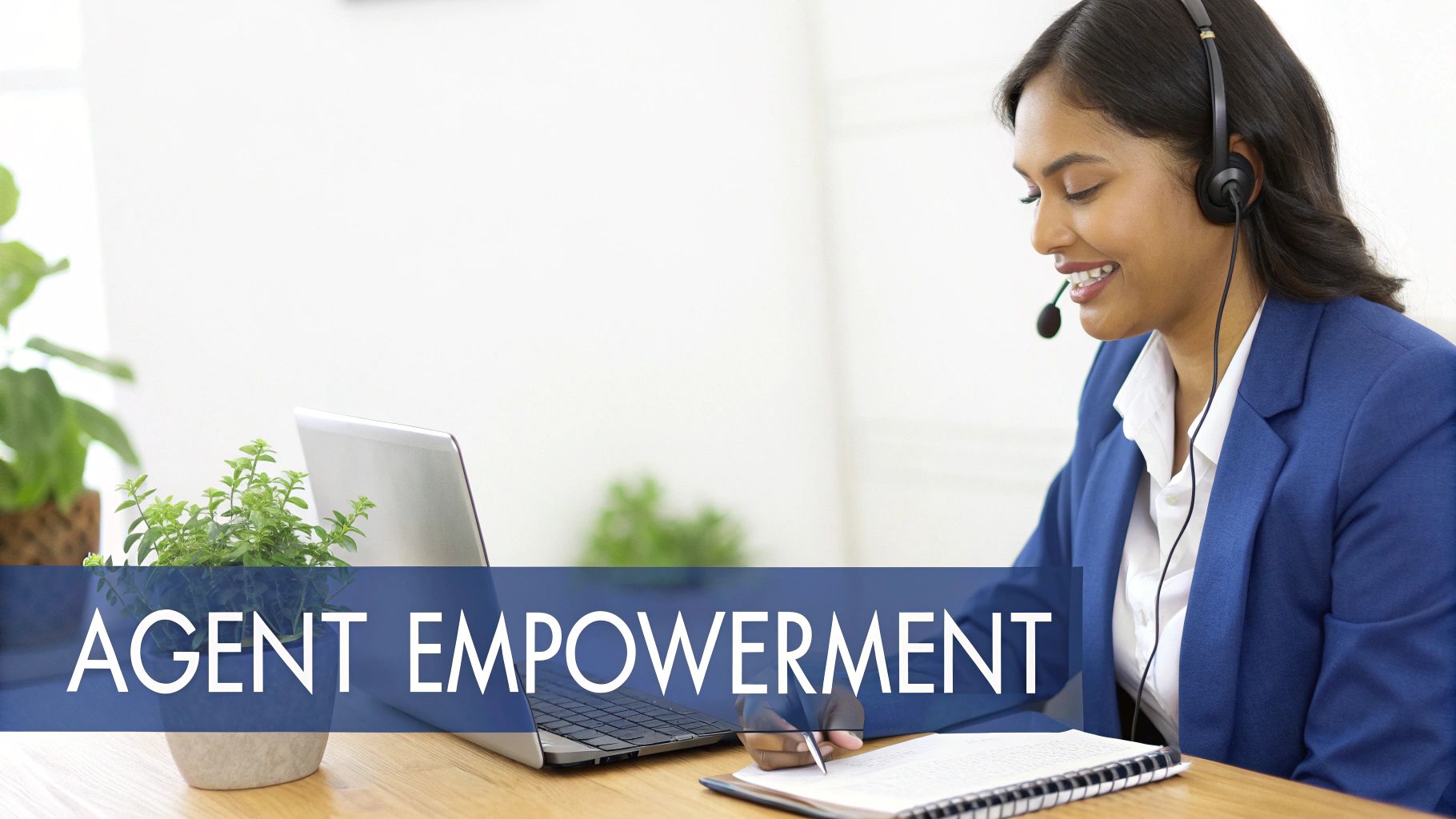Smiling contact center agent with a headset writing, symbolizing agent empowerment at her desk.