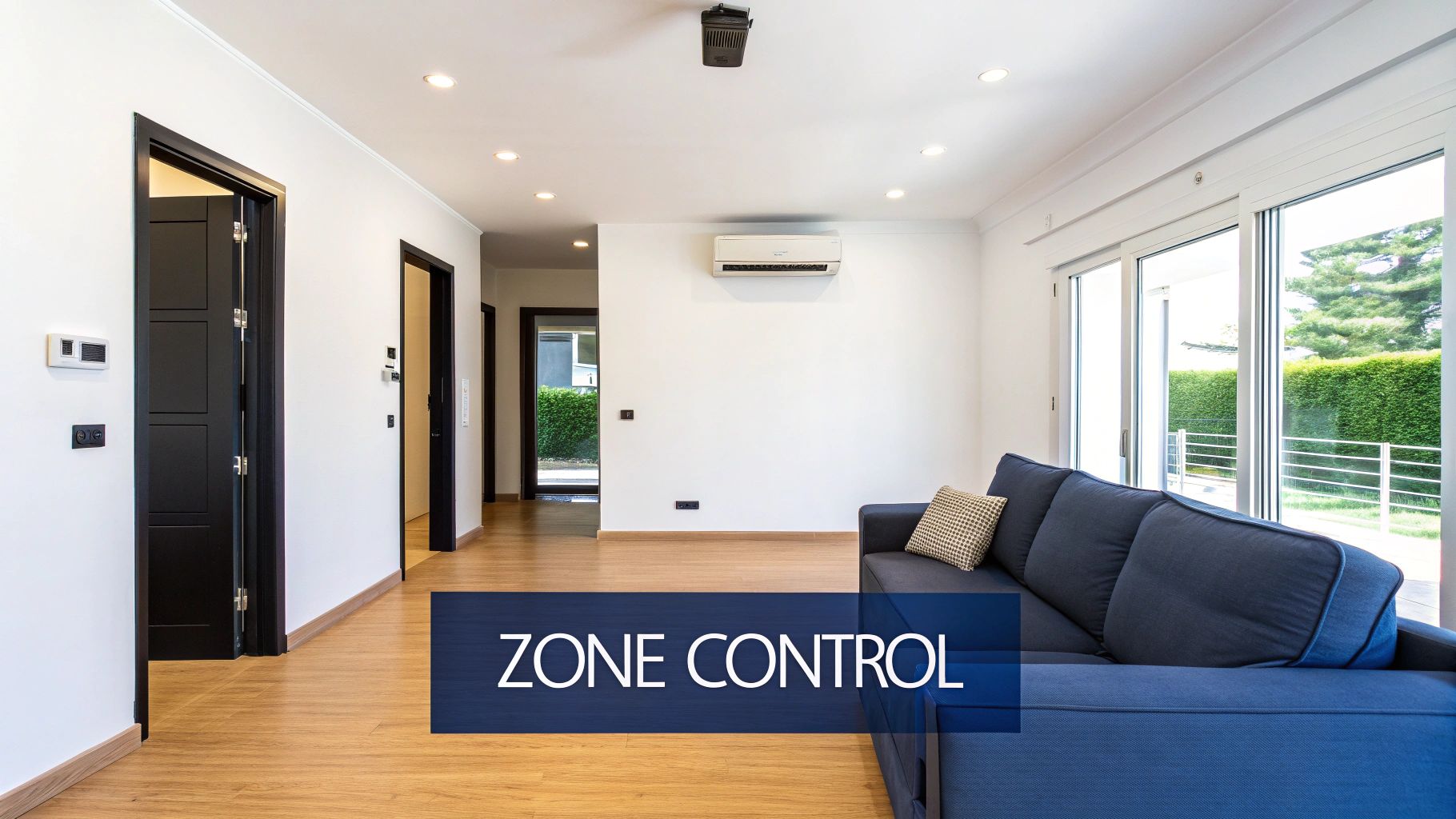 A bright living room with a blue sofa, wooden floor, and a split system air conditioner, highlighting zone control.