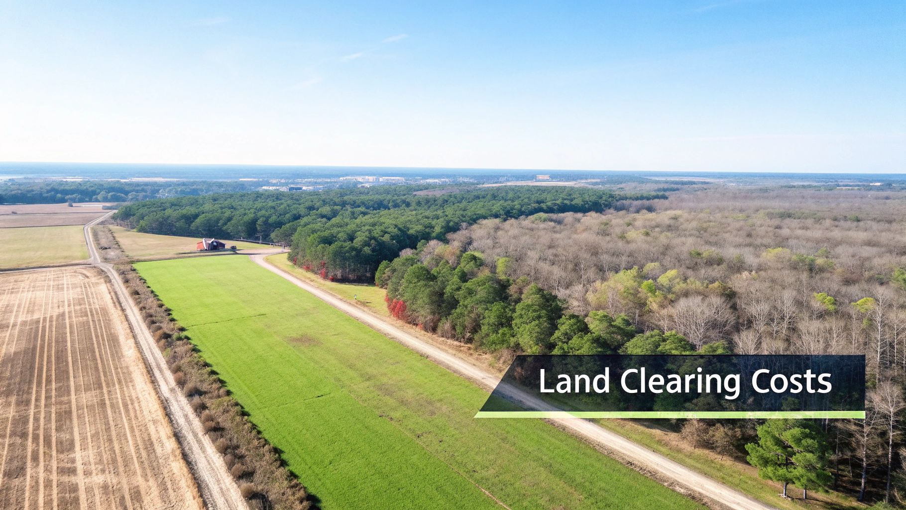 Aerial view of a rural landscape with agricultural fields, forests, a red barn, and dirt roads.