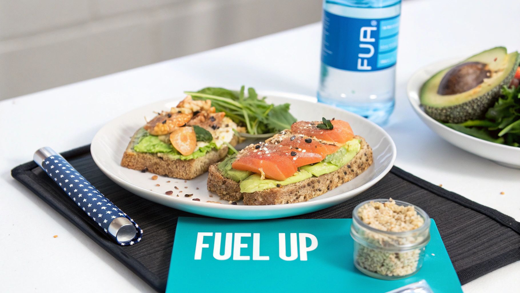 Two gourmet avocado toasts with salmon and kumquat, a side salad, water, and granola for a healthy meal.