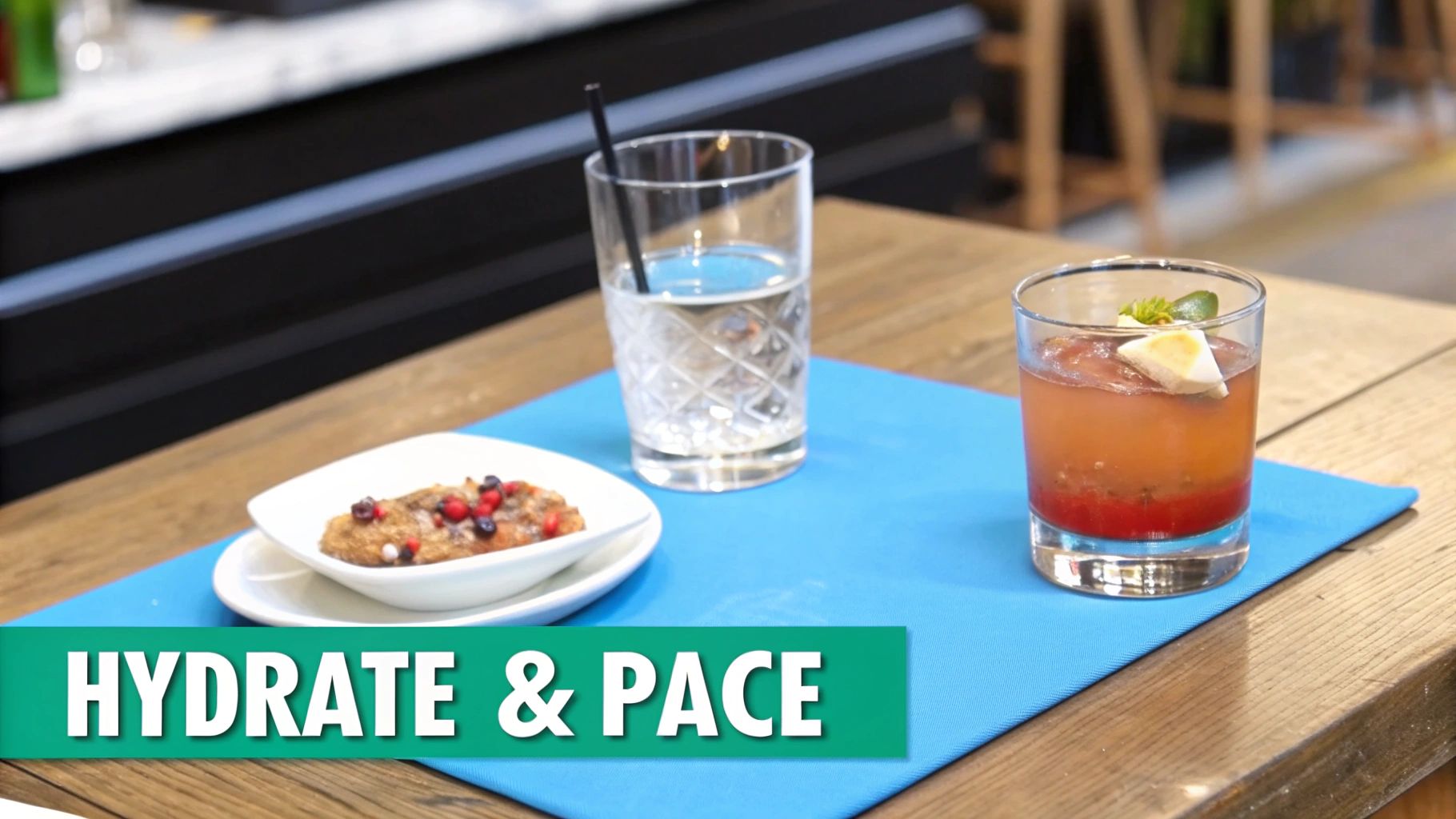 A wooden table features a blue placemat with a glass of water, a colorful cocktail, and a berry-topped dessert, promoting hydration.