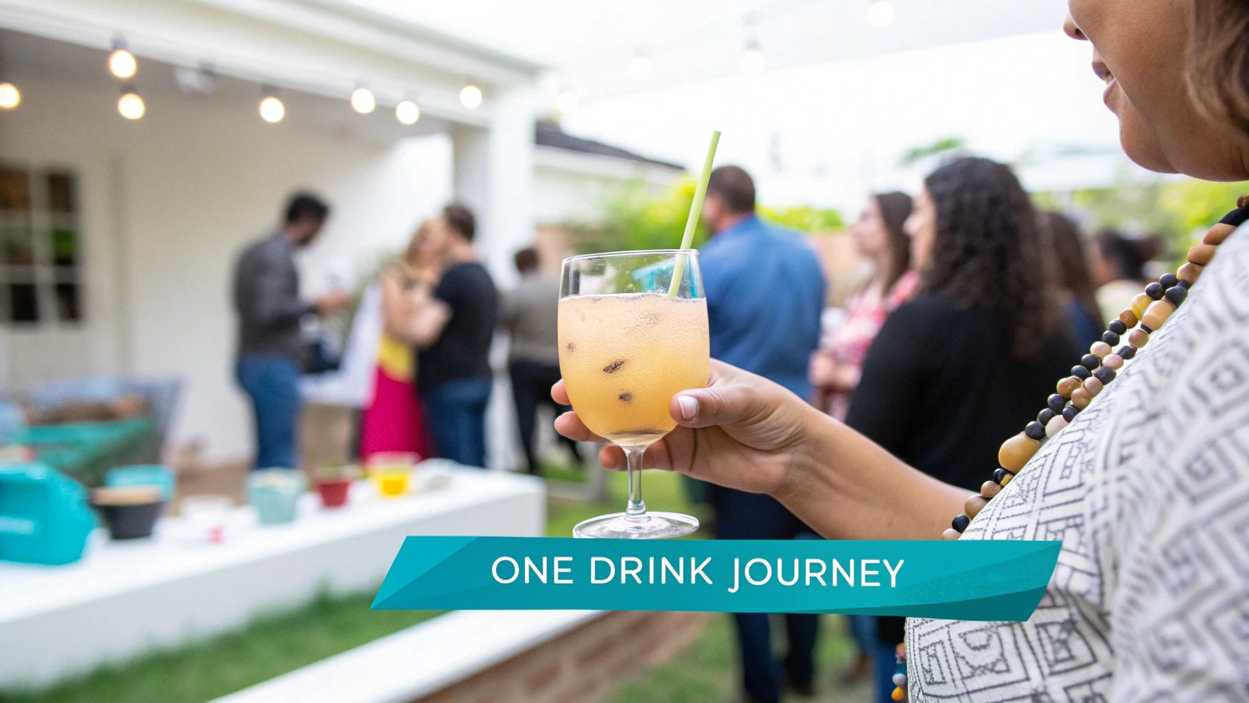 A person holds a bubbly drink with a straw at a lively outdoor gathering.