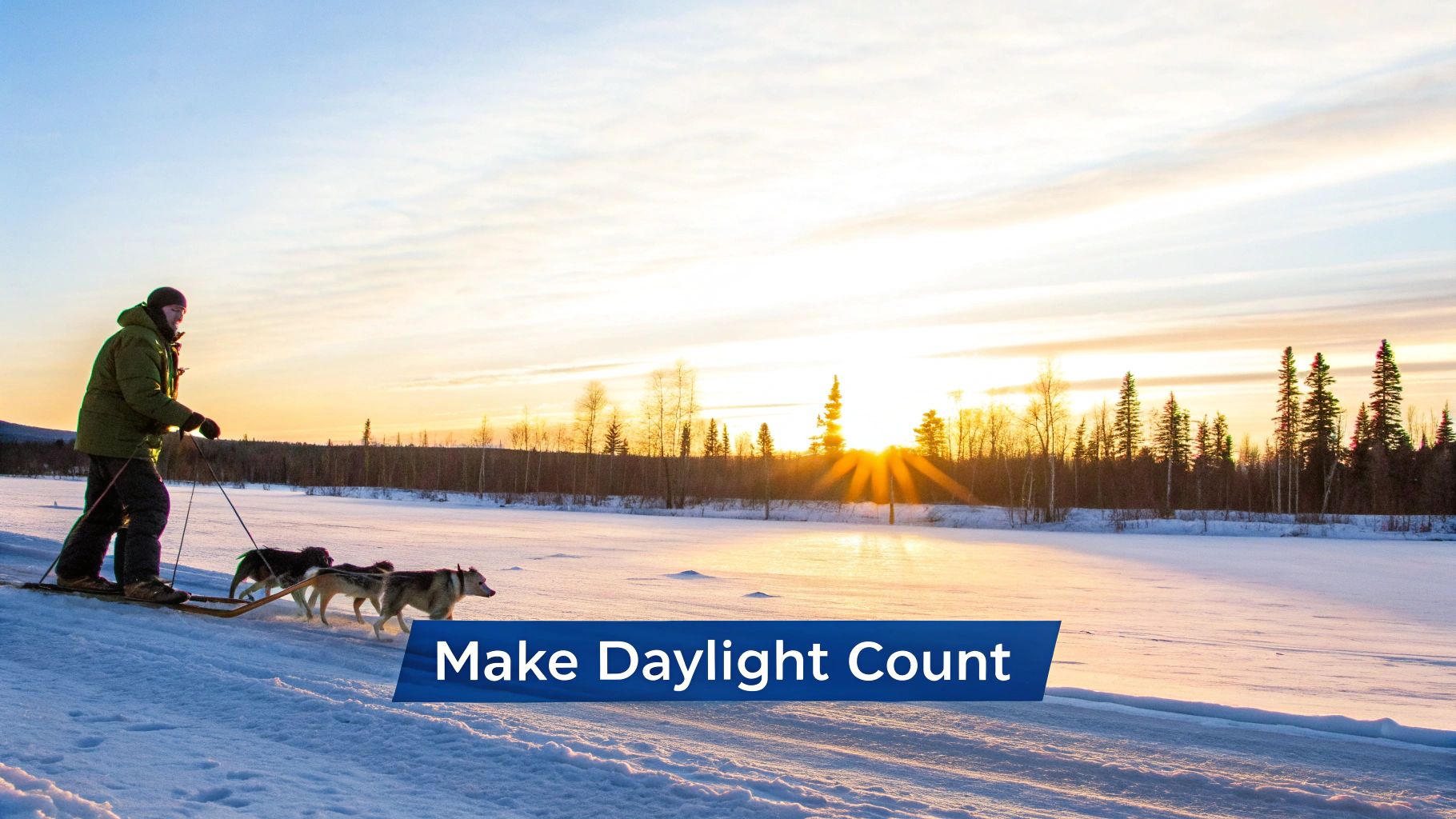 A person dog sledding with three huskies on a snowy trail at sunset in a winter landscape.
