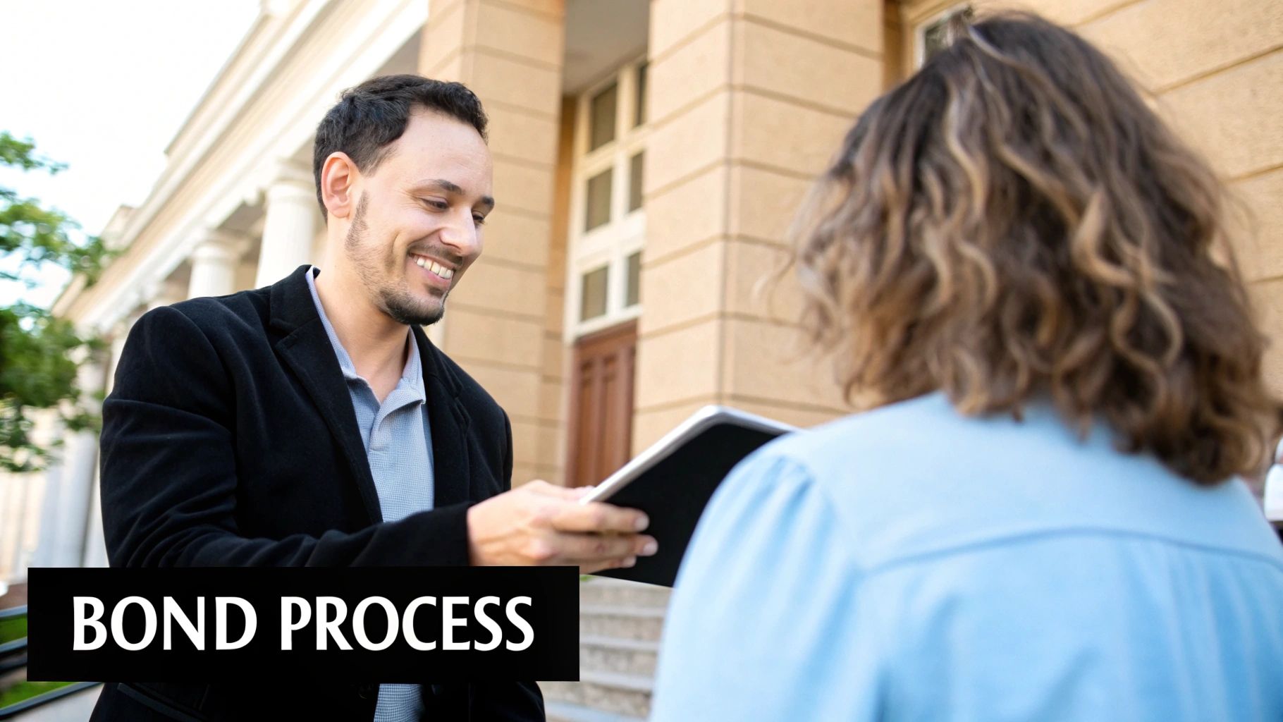 A smiling man hands a document to a woman, discussing the bond process outside a building.