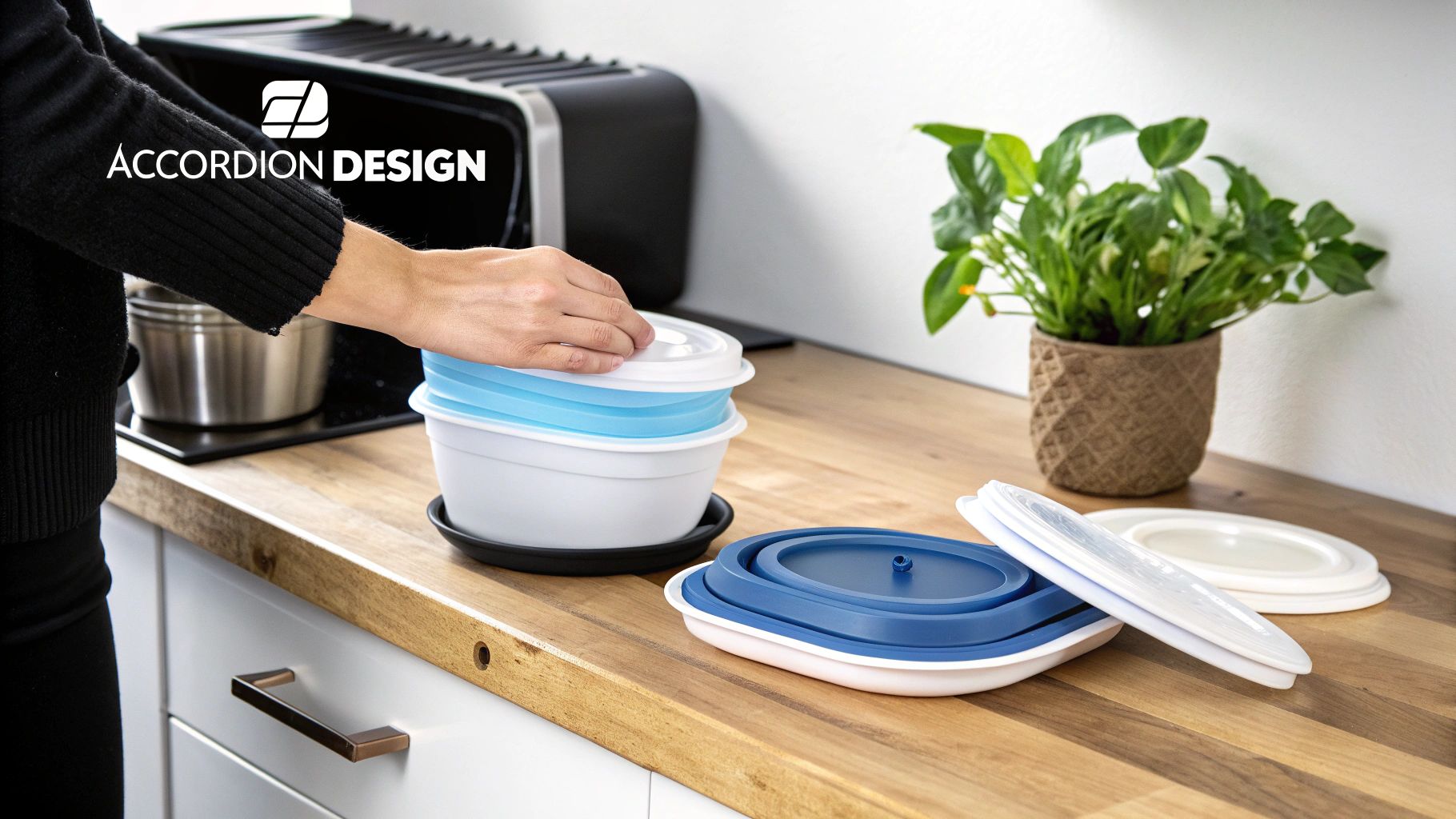 Person's hand stacking blue and white collapsible silicone food containers on a wooden kitchen counter.