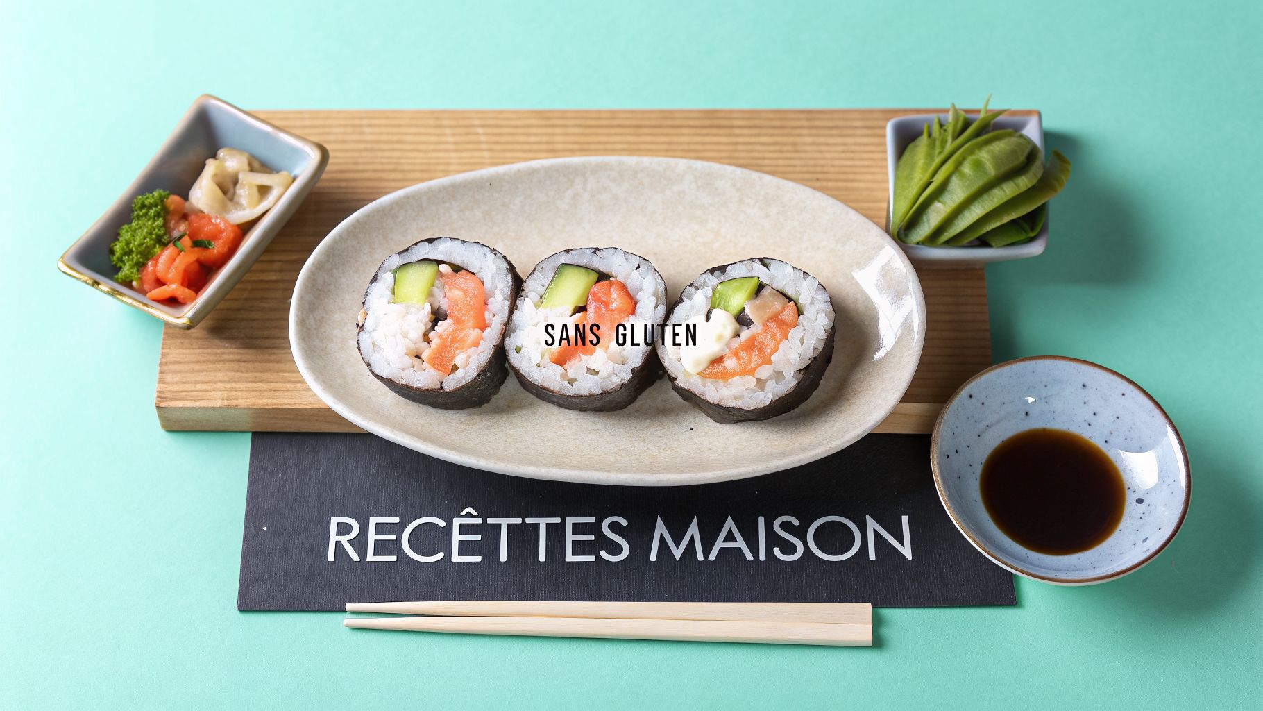 Trois rouleaux de sushi sans gluten sur une assiette, accompagnés de sauce soja et wasabi.