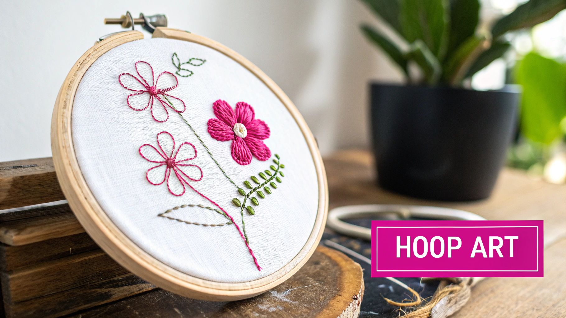 Pink floral embroidery hoop art with beginner-friendly stitches displayed on rustic wooden surface