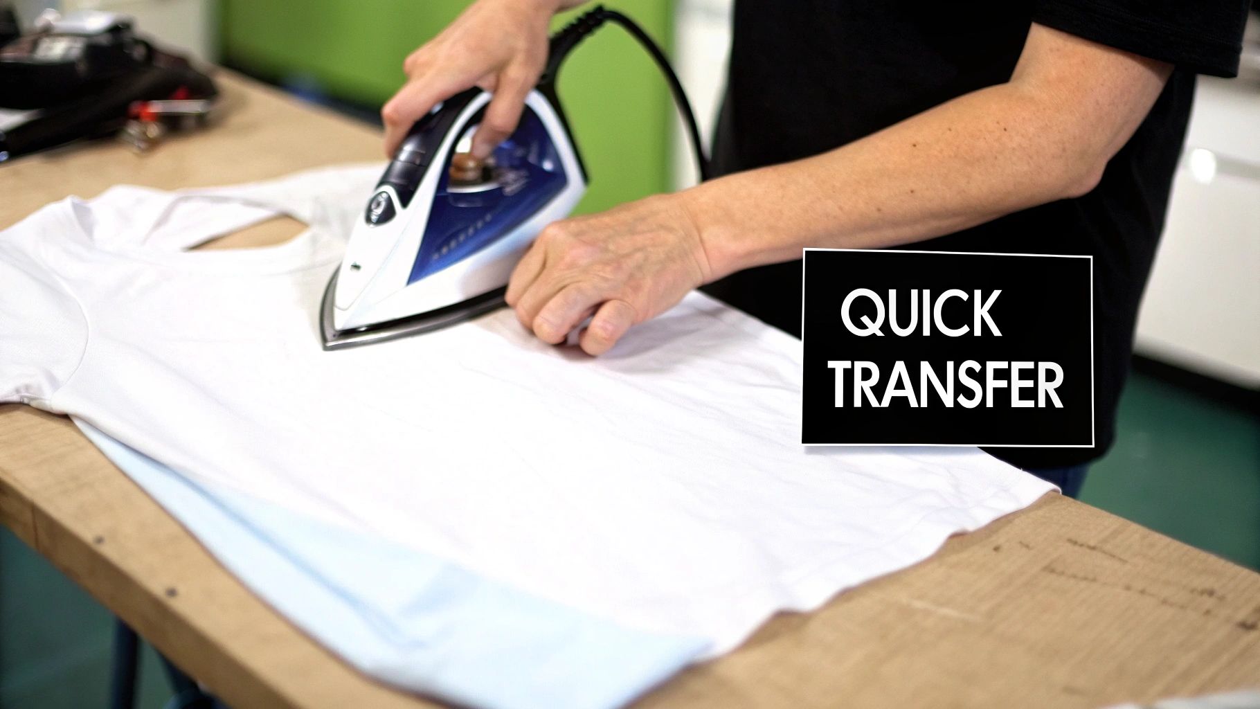 Close-up of hands ironing a white t-shirt on a wooden surface with a blue and white steam iron.