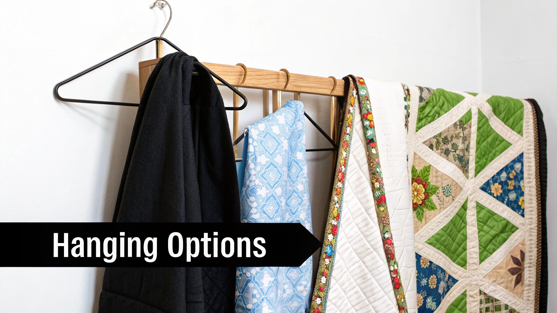 A modern wooden quilt hanger clamping the top of a colorful quilt against a white wall.