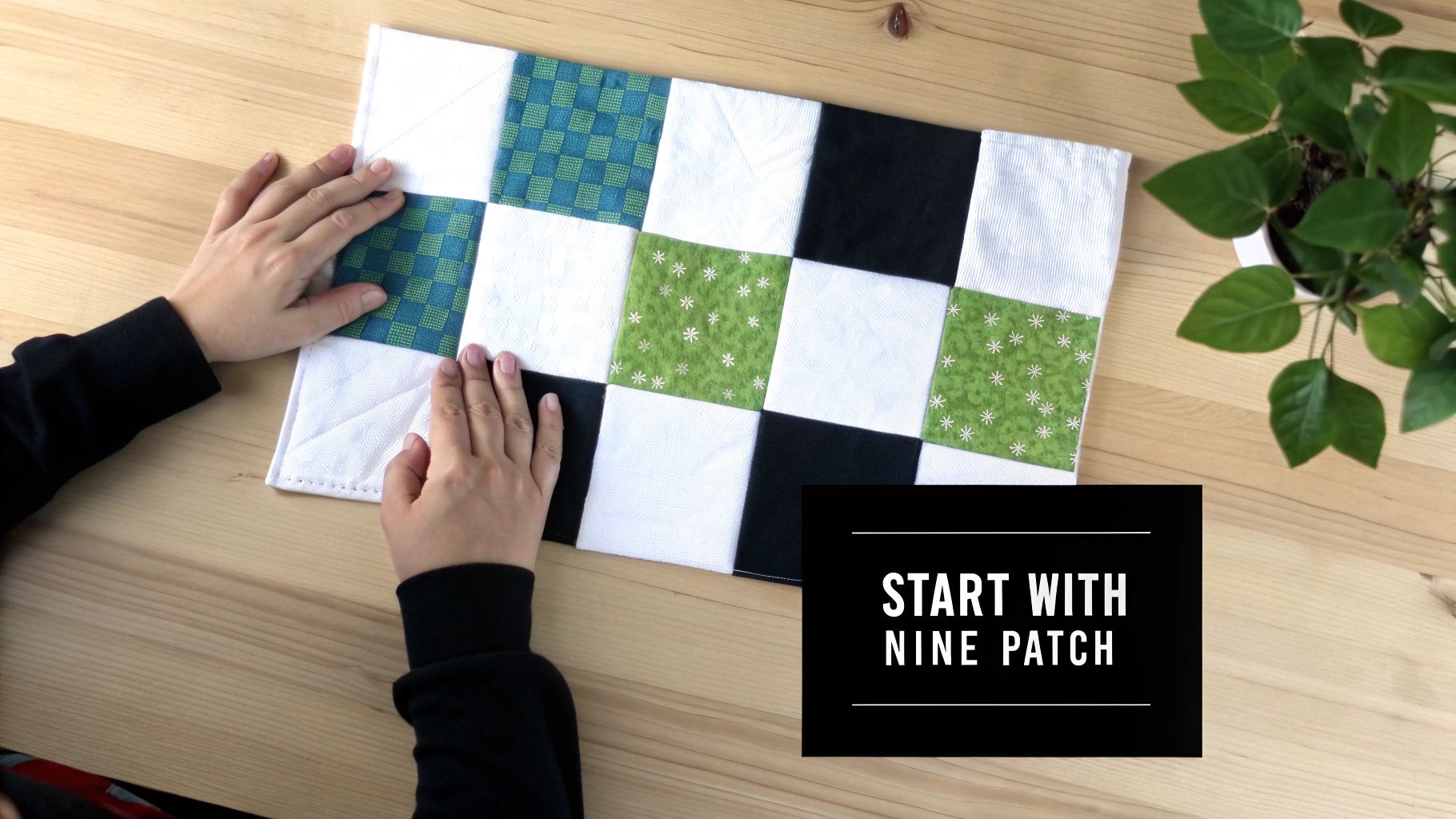 Hands gently touch a colorful nine-patch quilt block with various patterns on a light wooden table.