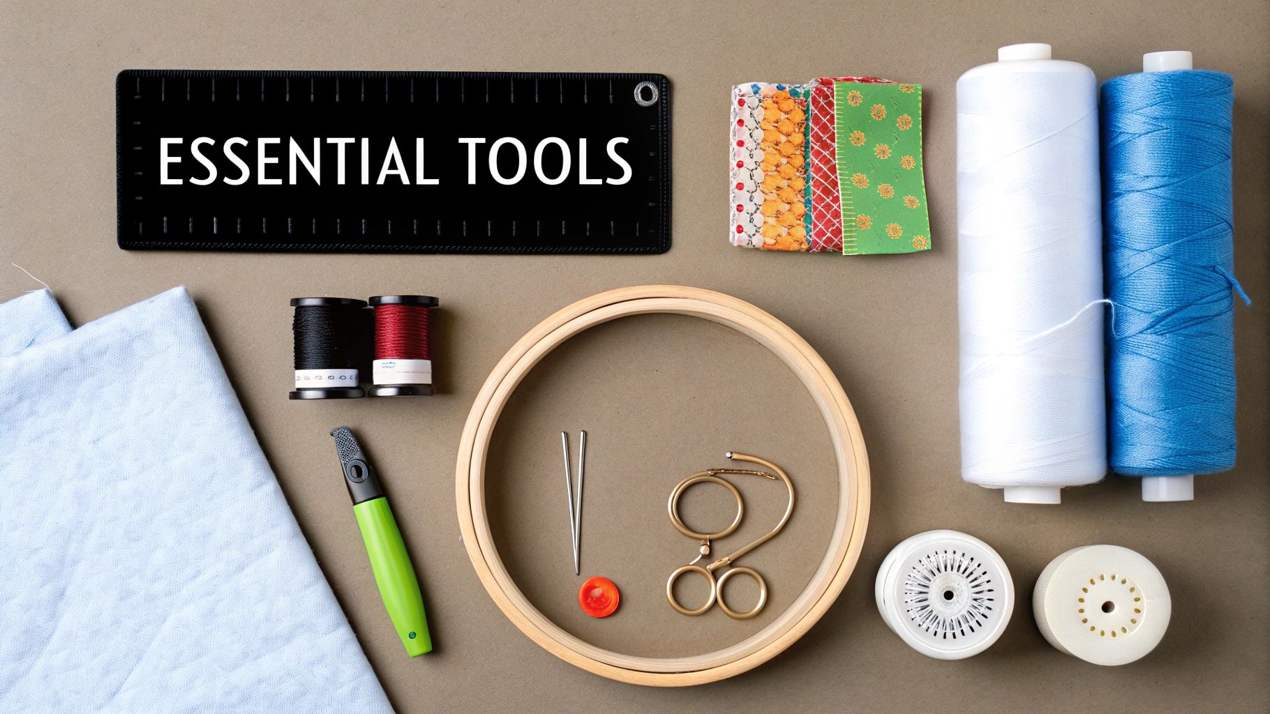 A flat lay of essential quilting and sewing tools, including threads, fabric, hoop, and scissors on a beige background.