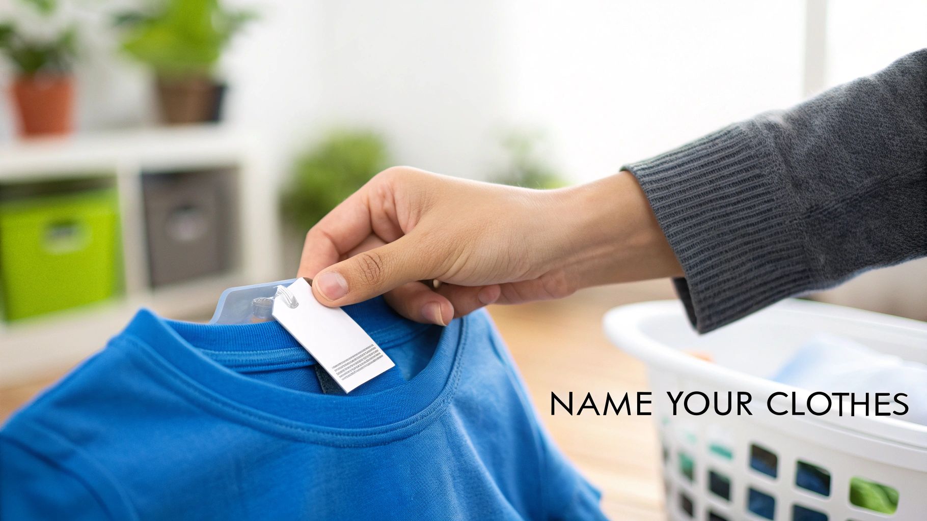 A hand holds a blue t-shirt with a white label tag, suggesting clothing organization.