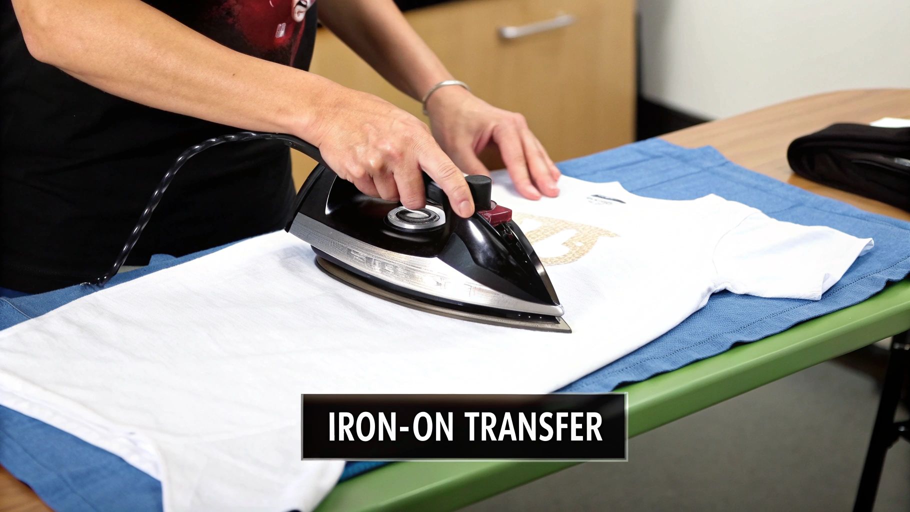 Close-up of a person using an iron to apply an iron-on transfer onto a white t-shirt.