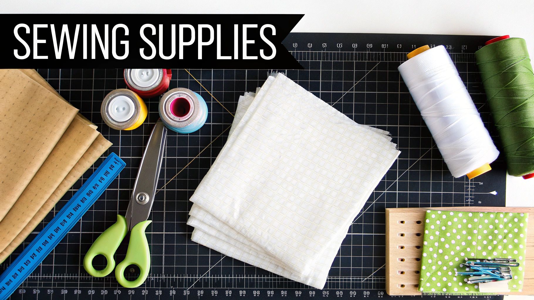Flat lay of diverse sewing supplies, including fabrics, thread, scissors, ruler, and clips on a cutting mat.
