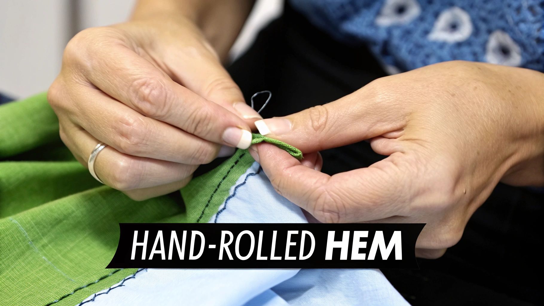 Close-up of hands demonstrating a hand-rolled hem on green fabric with a needle and white thread.