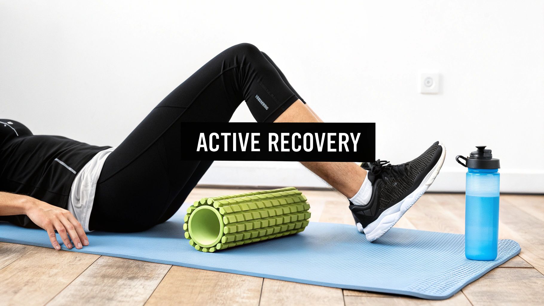Person lying on a blue yoga mat with a green foam roller and a blue water bottle for active recovery.