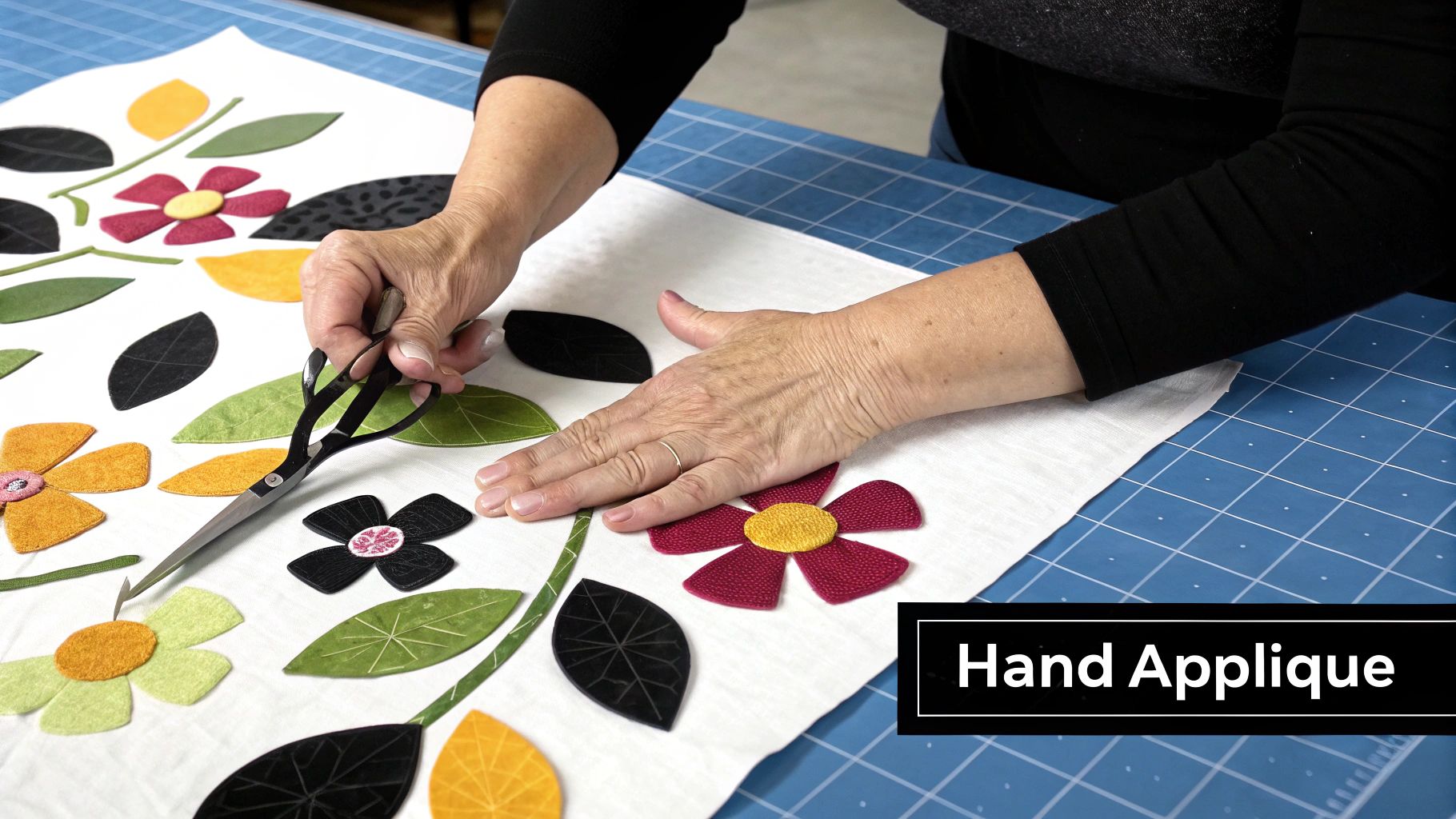 Hands using scissors to cut fabric flowers and leaves for hand applique quilting project