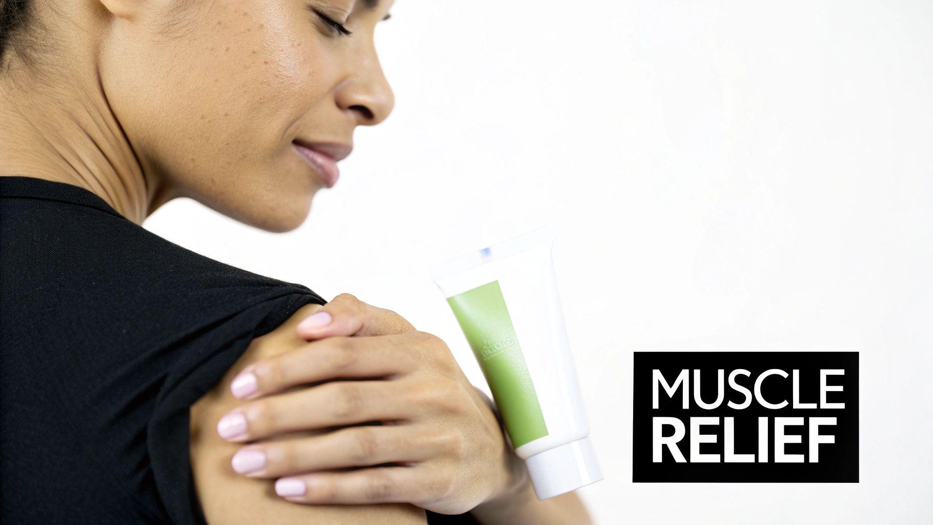 A woman gently applies muscle relief cream to her shoulder, holding a white and green tube.