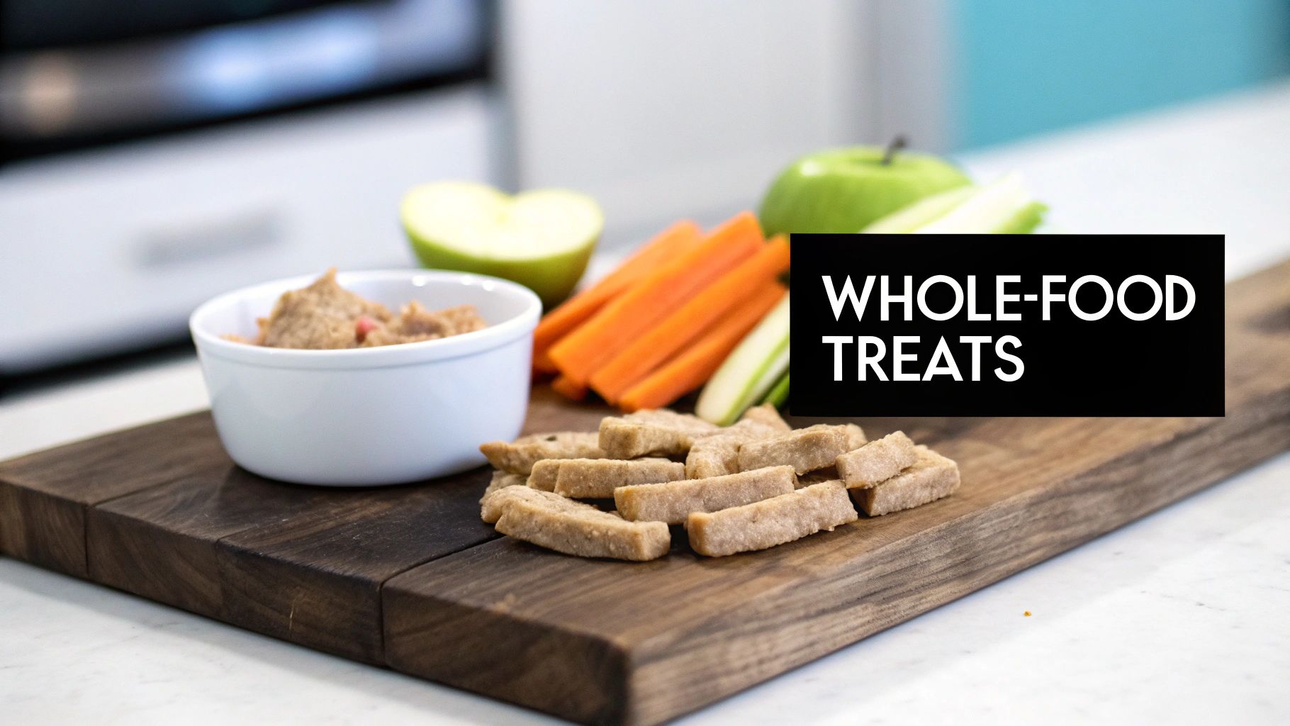 A wooden board displaying whole-food treats for dogs: a bowl of paste, carrots, apple slices, and baked biscuits.