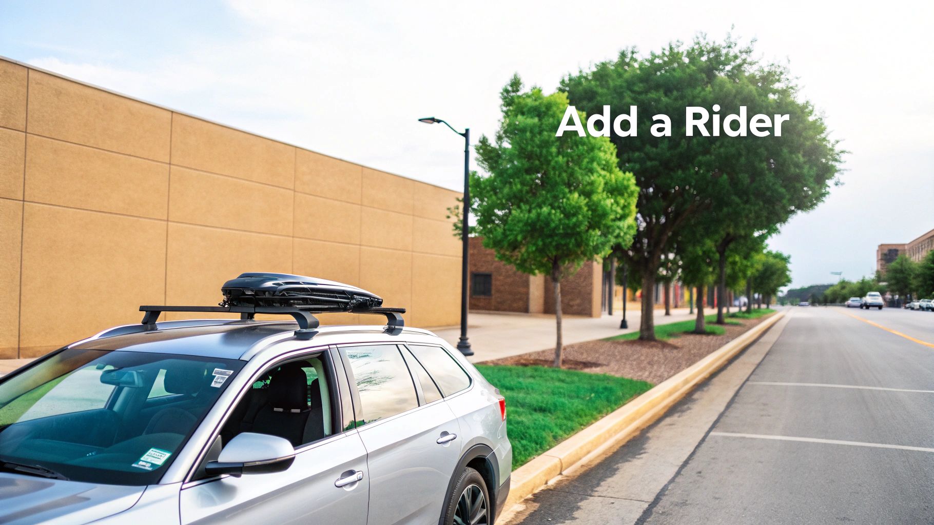 Silver SUV with a roof rack and cargo box parked roadside, displaying 'Add a Rider' text.