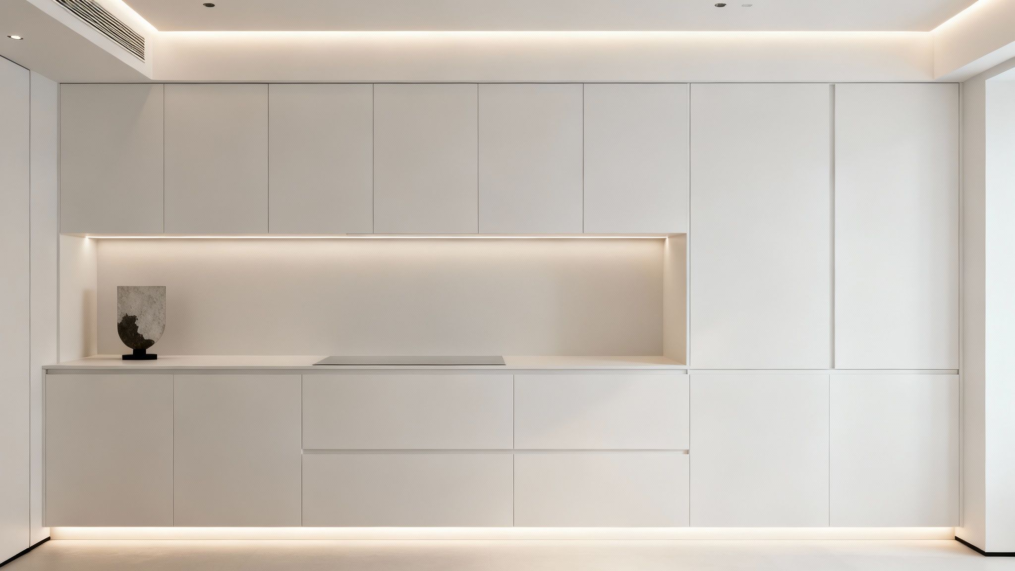 Modern white minimalist kitchen cabinetry with integrated lighting, sleek countertop, and a decorative object.