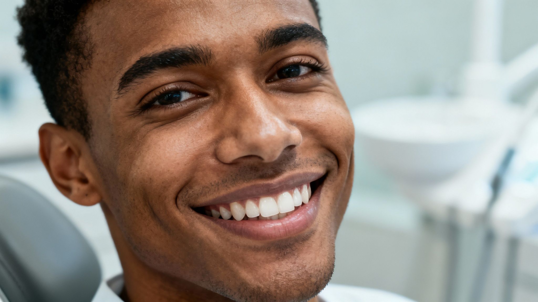 Happy young Black man with a bright smile and white teeth at the dentist.