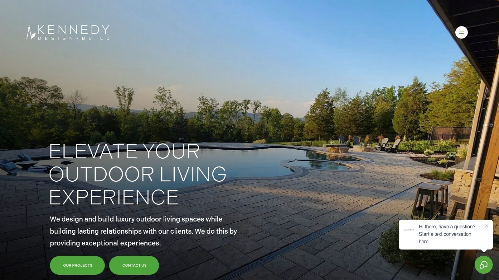 A beautifully crafted stone patio with an integrated fire pit and seating wall, showcasing Kennedy Outdoor Living's high-end hardscape design.