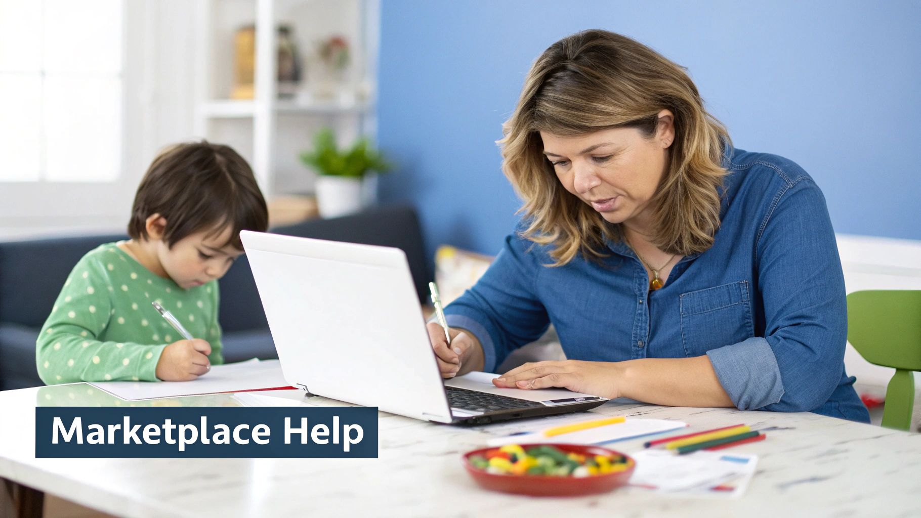 A mother works on her laptop and writes at a table next to her child who is drawing.