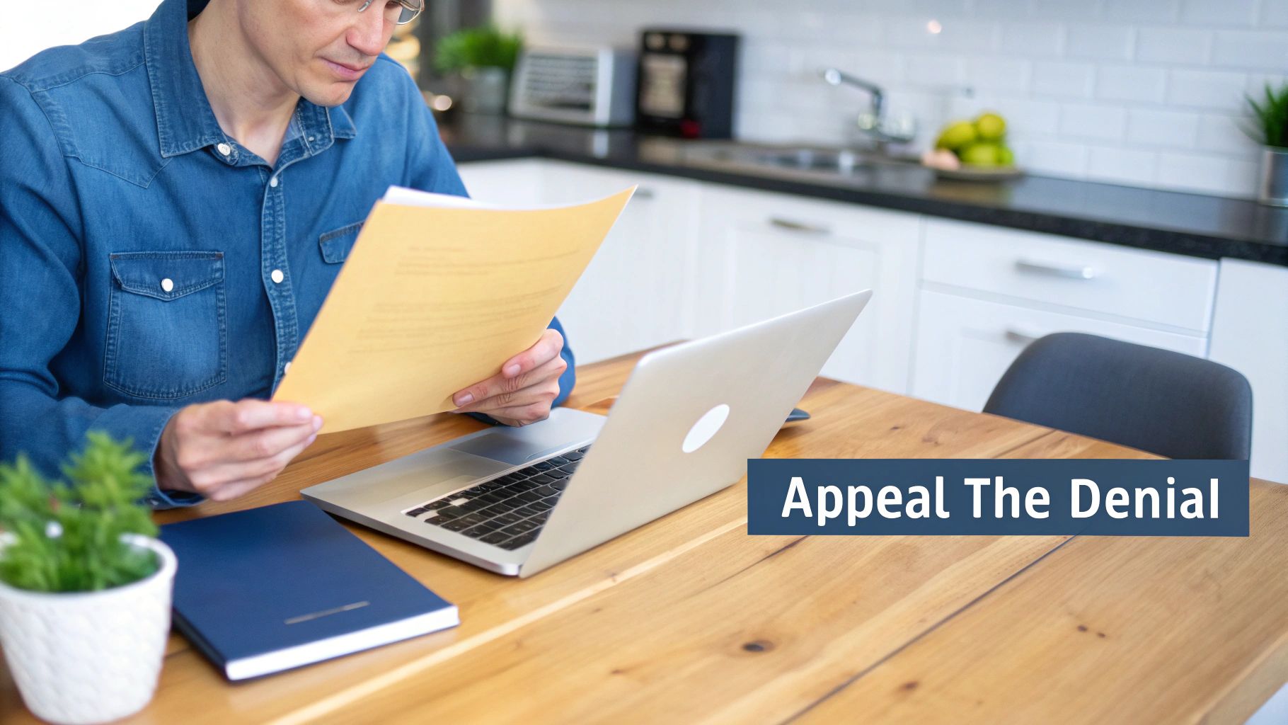 A person sitting at a desk, looking stressed while reviewing insurance paperwork and a laptop.