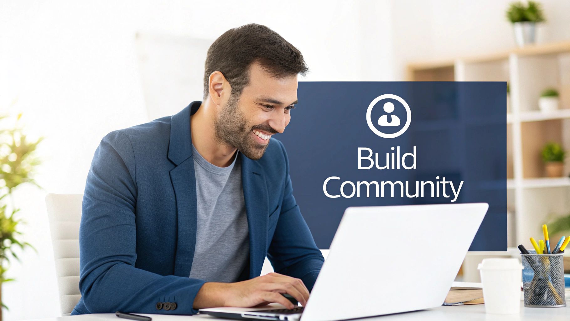 A smiling man in a blue blazer works on a laptop, with "Build Community" on a monitor.
