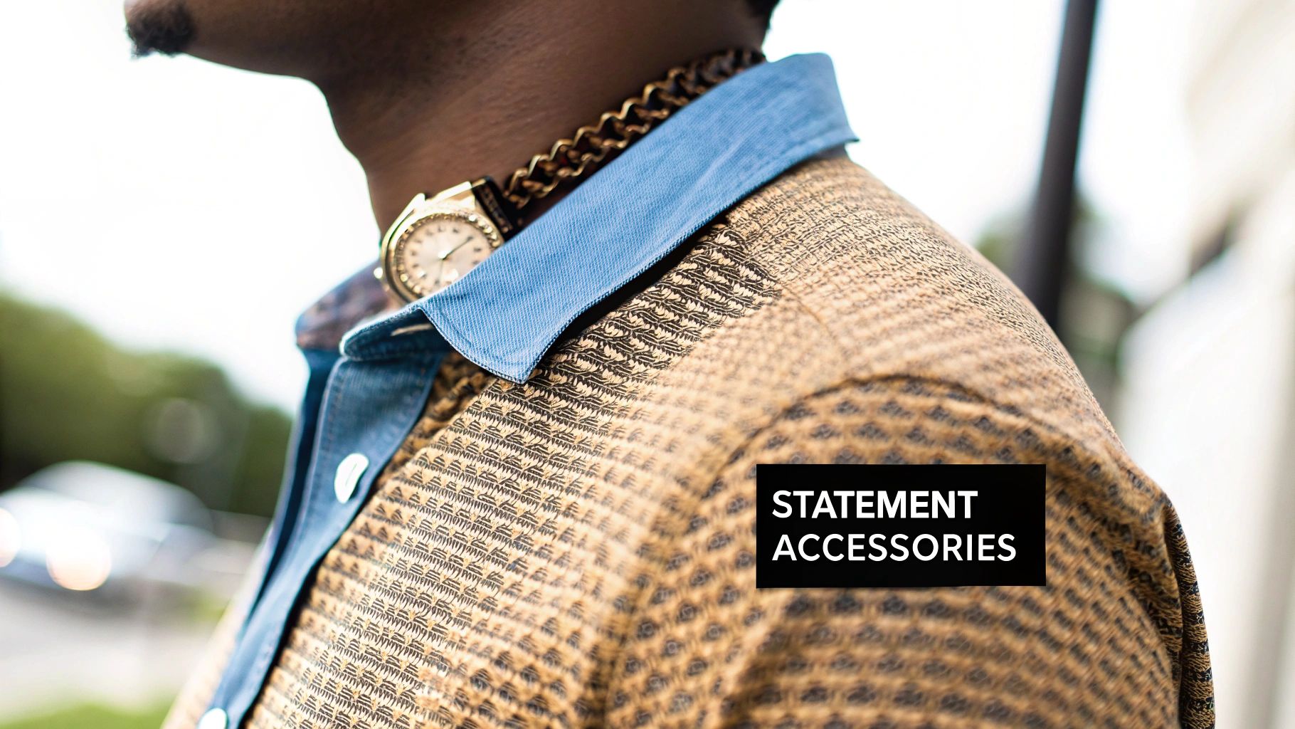 Close-up of a person wearing a patterned shirt, a gold chain, and a gold watch.