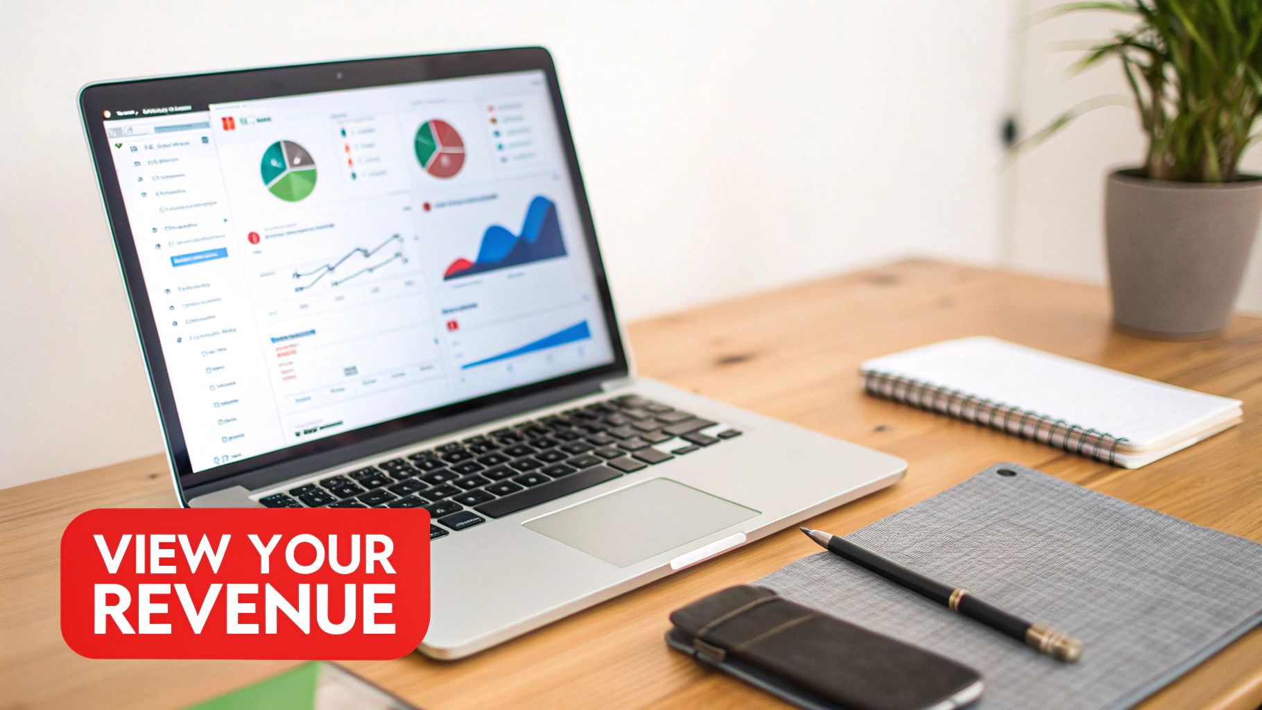 A laptop displaying revenue analytics and charts on a wooden desk, with a 'VIEW YOUR REVENUE' call to action.