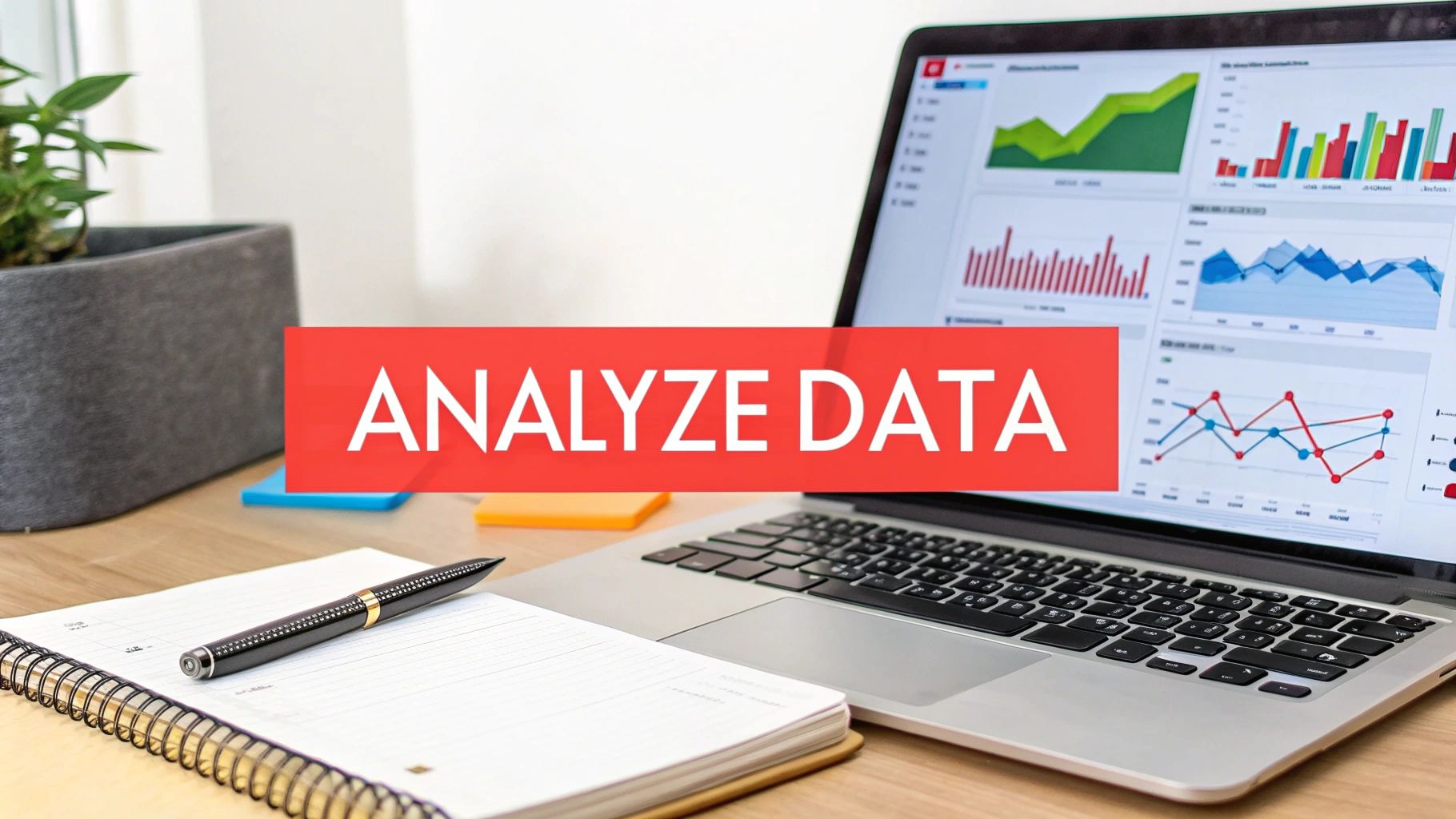 A laptop displaying data analysis charts on a desk with a notebook, pen, and a banner reading 'ANALYZE DATA'.