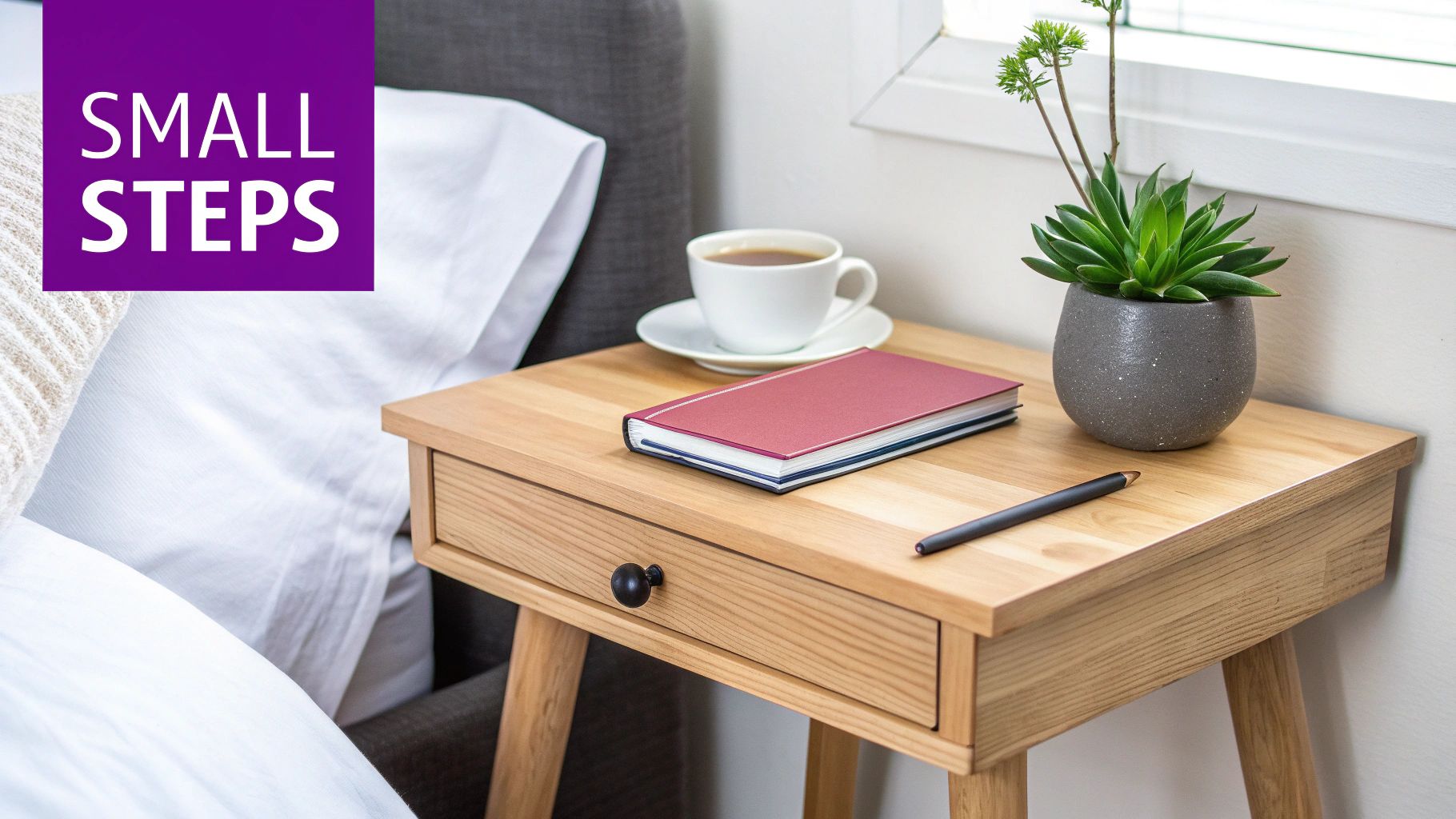 Wooden nightstand with coffee, a red journal, a pen, and a green succulent plant.
