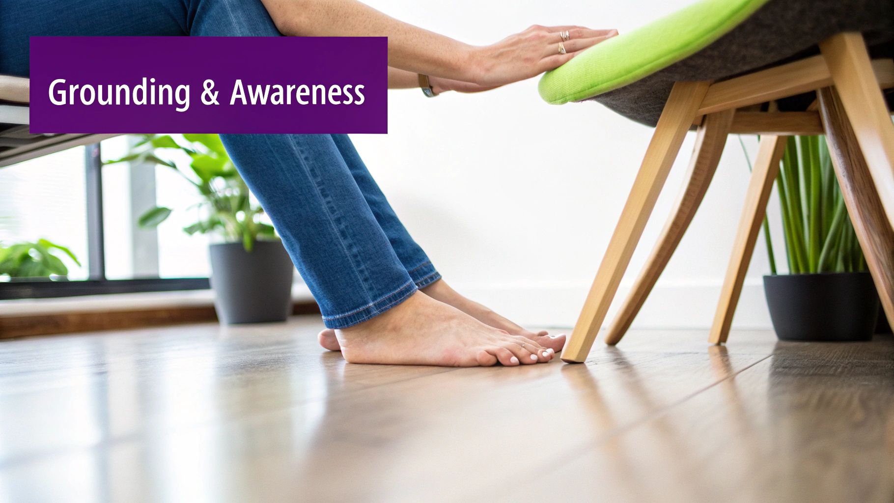 Person with bare feet and jeans touches a chair, practicing grounding and awareness on a wooden floor.